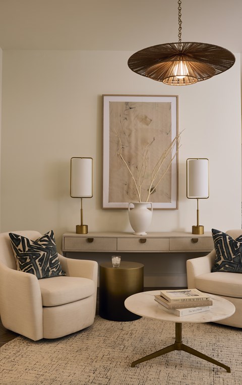 A living room with a white chair, a white sofa, a gold side table, and a gold floor lamp.